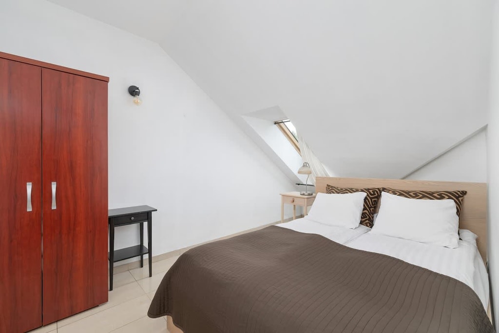 Cozy attic bedroom with a brown bedspread and red wardrobe.