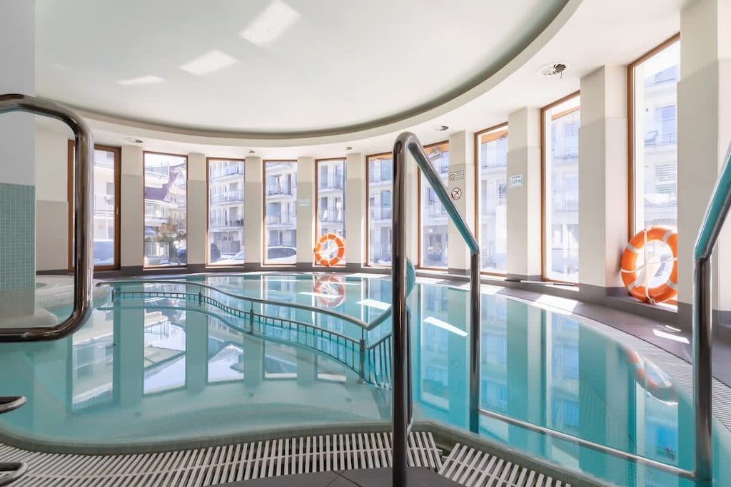 Bright area with large windows and pool access via metal stairs.