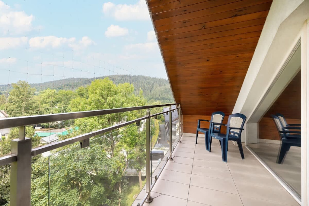 Outdoor space with table and chairs overlooking greenery and hills.