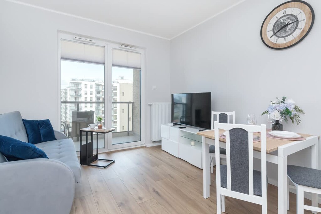 A bright living and dining area with a blue couch and balcony access. Perfect space for relaxing or hosting friends.