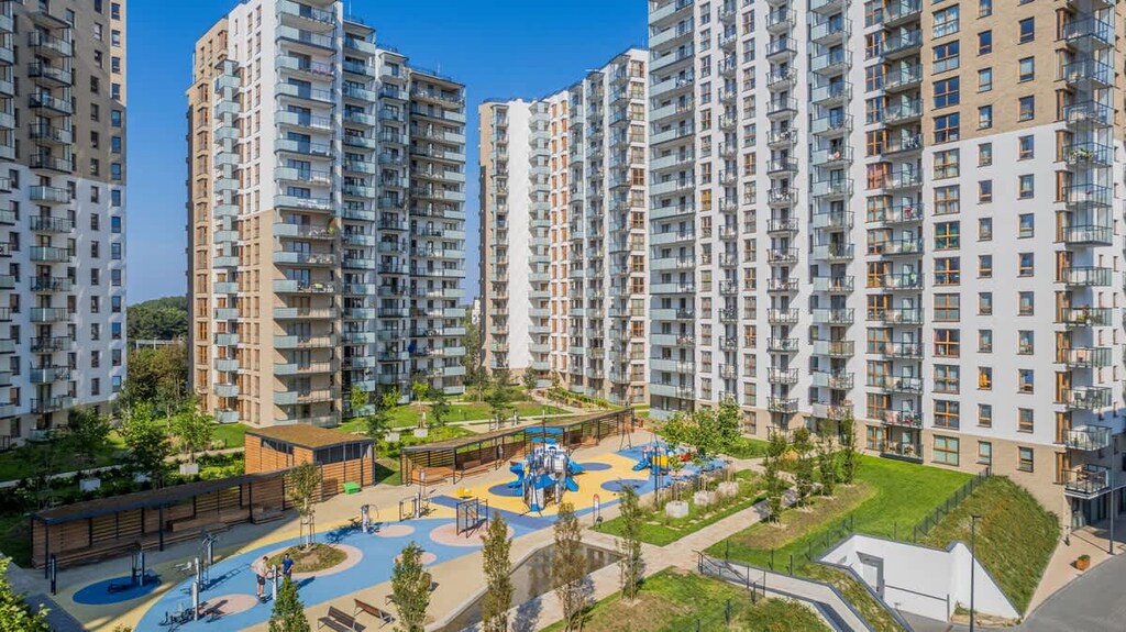 A view of a modern residential building with green outdoor areas. The complex looks clean and family-friendly.