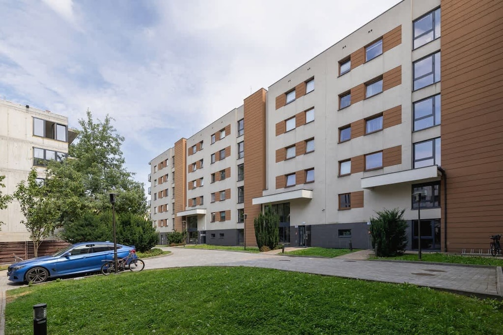 Outside view of an apartment block with green grass and trees in the foreground.