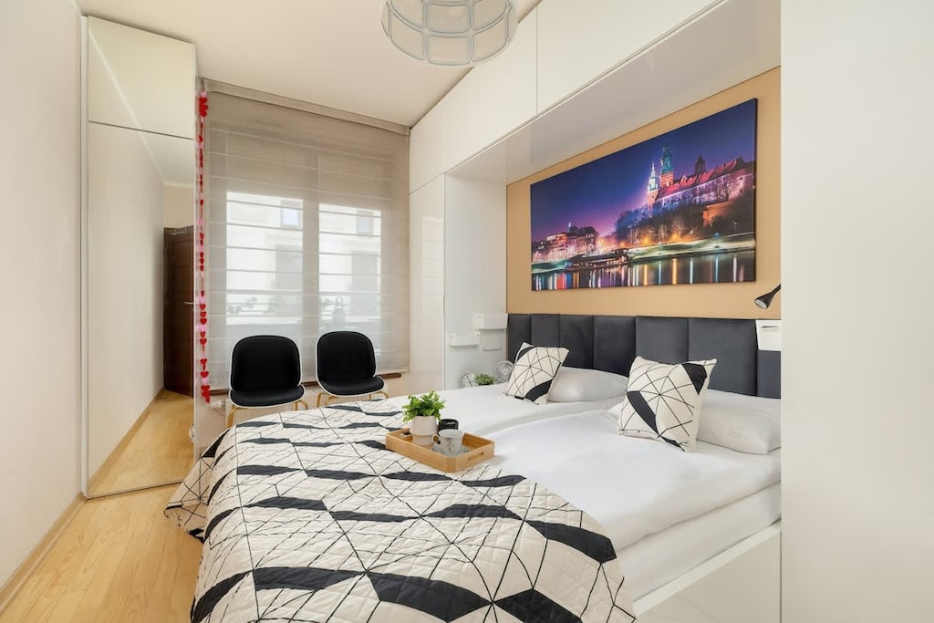A modern bedroom with a double bed, abstract artwork above the headboard, and a wardrobe with sliding doors.