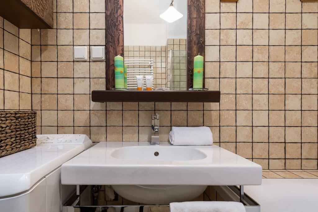 A bathroom with beige tiled walls, featuring a bathtub, a washing machine, and simple fixtures for a functional setup.