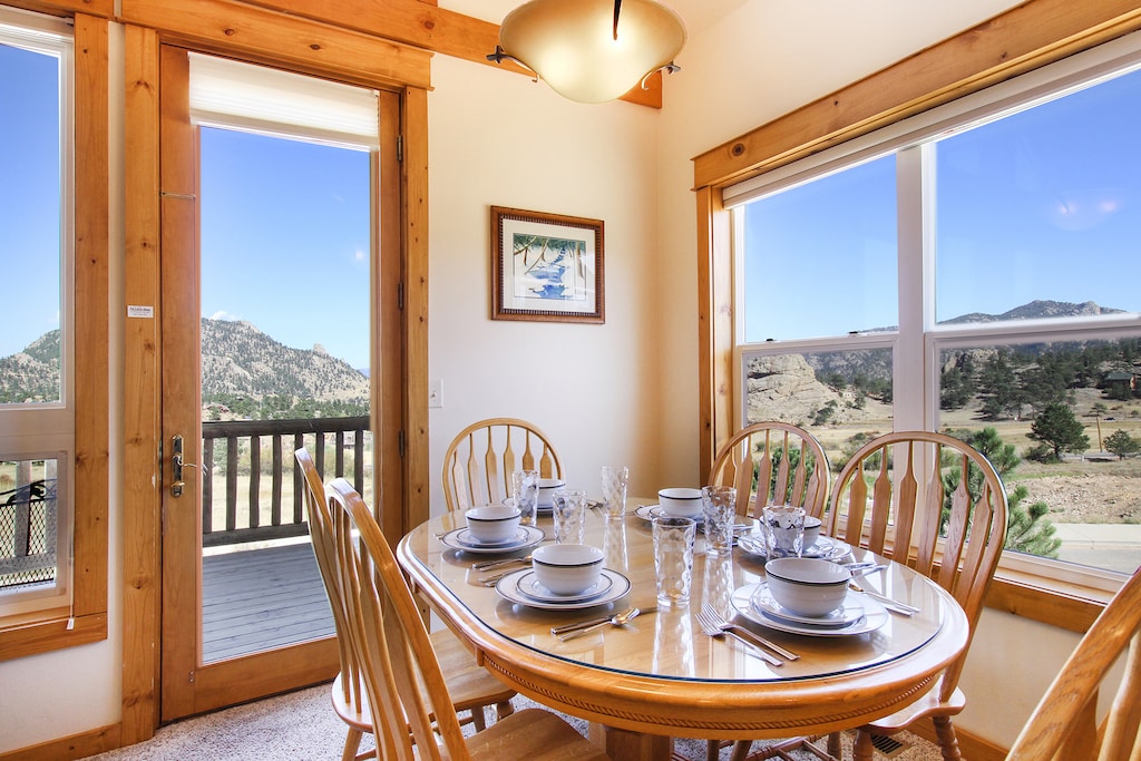 Dining table with seating for six surrounded by windows and beautiful mountain views.