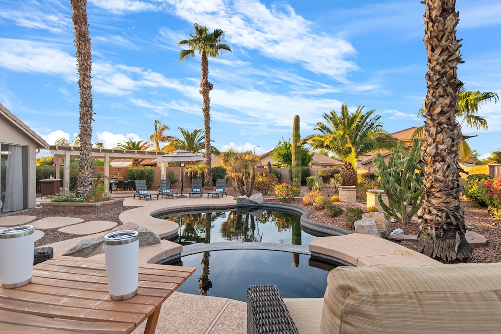 Tropical backyard oasis with a serene pool, palm trees, and comfortable outdoor seating.