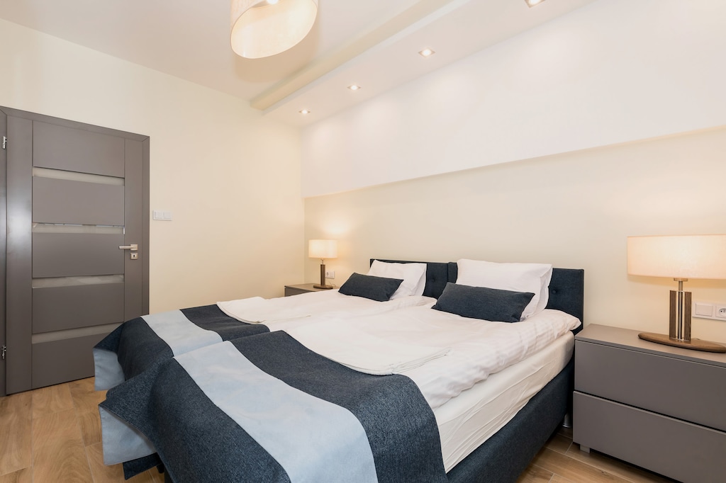 A neatly arranged bedroom with a large bed, modern gray furniture, and soft ambient lighting for a cozy atmosphere.