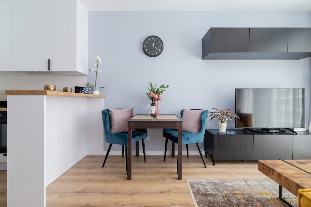 A dining area with a table, chairs, and an open kitchen in a modern layout.
