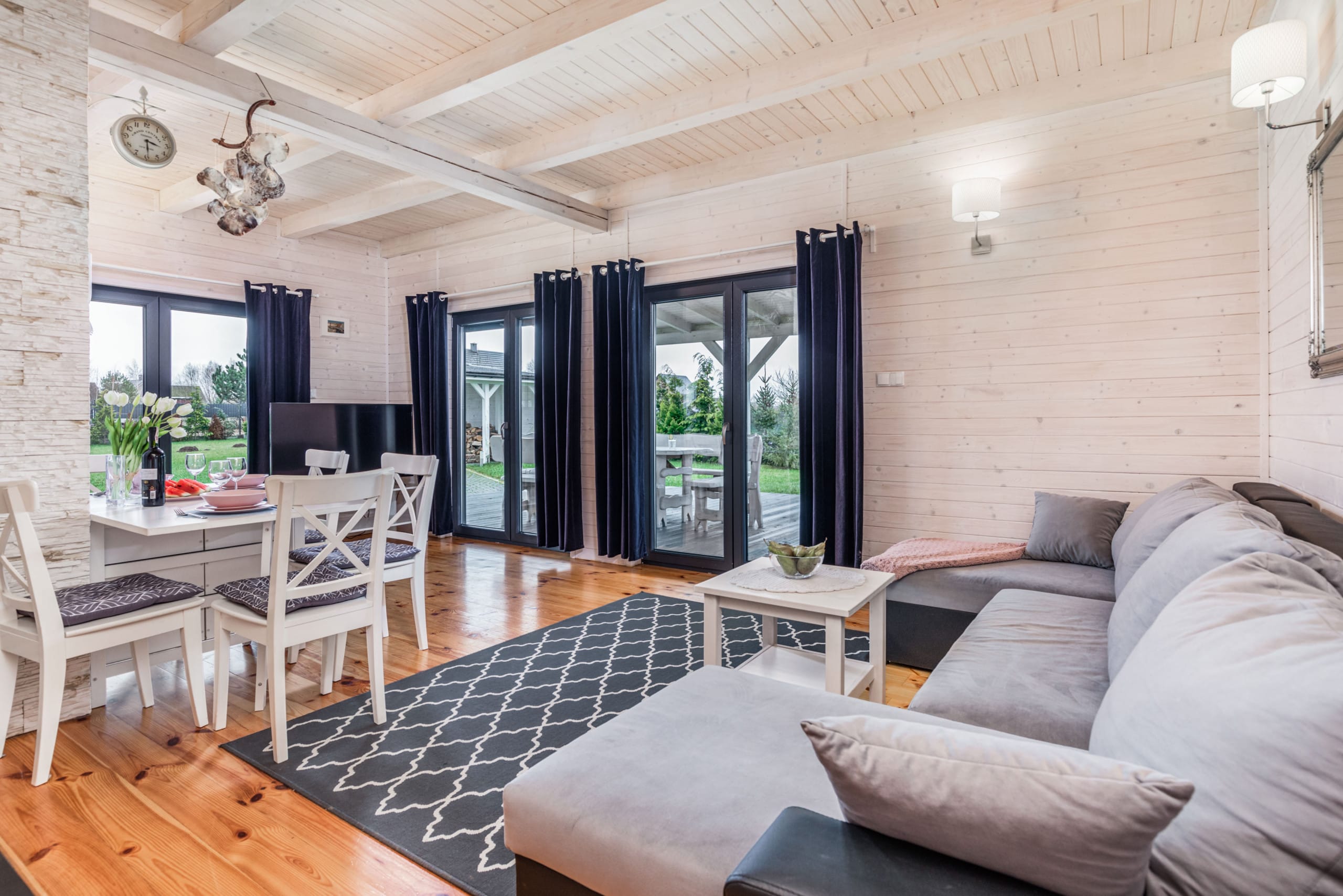 A contemporary and inviting living room featuring a gray sofa, accented by a large flat-screen TV and natural wooden floors. Perfect for relaxing or entertaining guests in a bright and vibrant setting.