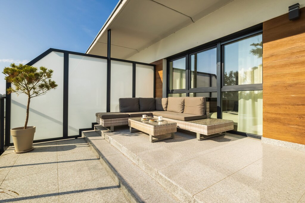 A spacious outdoor terrace with lounge chairs, wooden paneling, and views of the surrounding area.