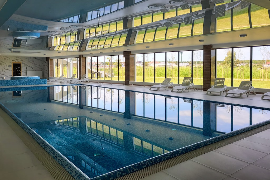 A luxurious indoor pool surrounded by large glass windows allowing natural light to flood the space.