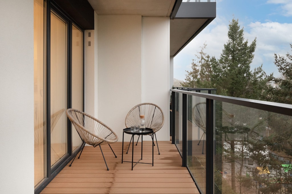 A balcony with outdoor chairs and a small table, offering a peaceful spot to enjoy the surrounding greenery.