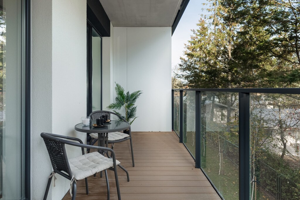 A balcony with outdoor seating and a view of surrounding greenery.
