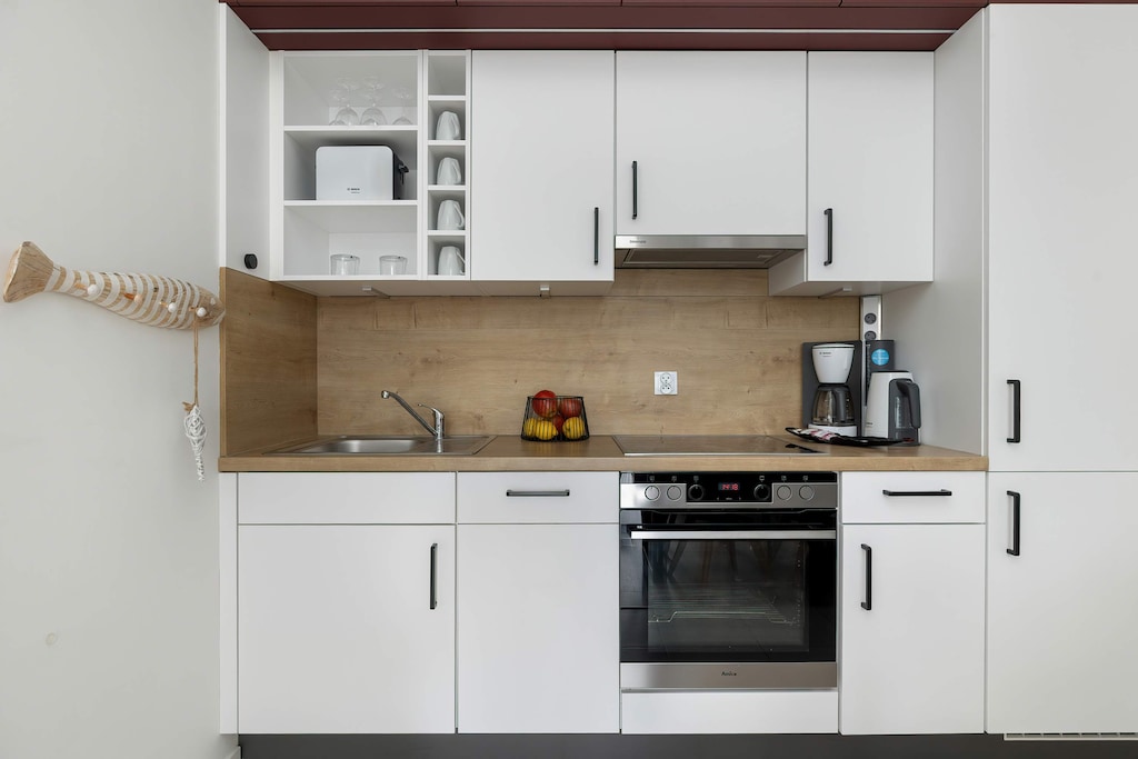 Nowoczesny aneks kuchenny ze sprzętami wysokiej jakości, które zapewniają możliwość przygotowywania domowych posiłków. 