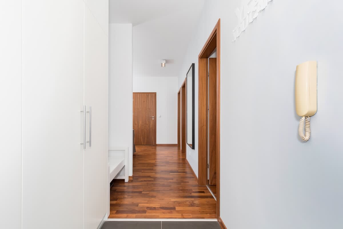 Hallway with white walls and a white wardrobe from which the entrance to the rooms leads. 