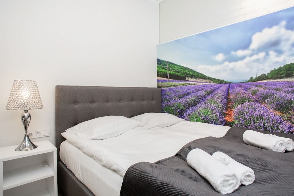 A bedroom with a neatly made bed, complemented by a vibrant piece of artwork on the wall, adding a pop of color.
