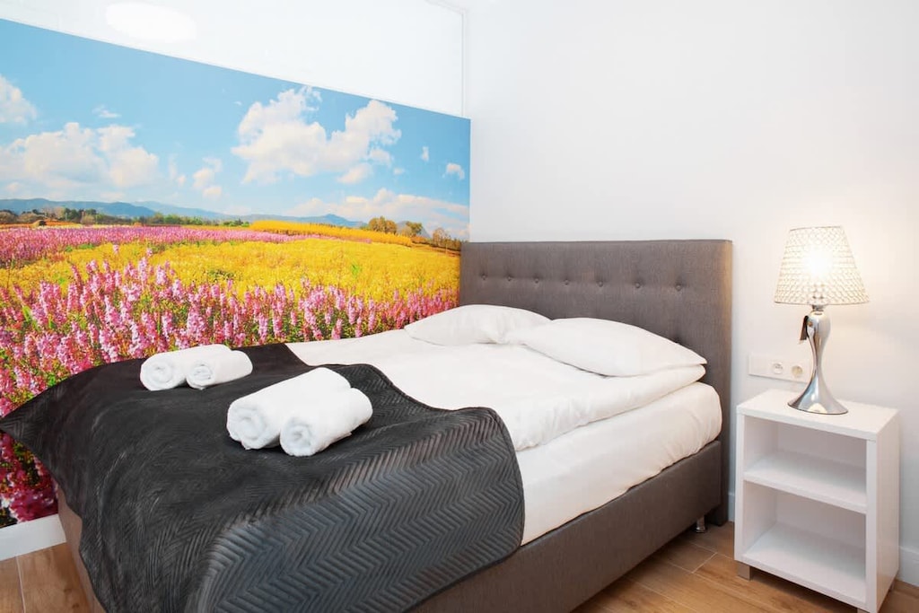 A bedroom with a neatly made bed, complemented by a vibrant piece of artwork on the wall, adding a pop of color.