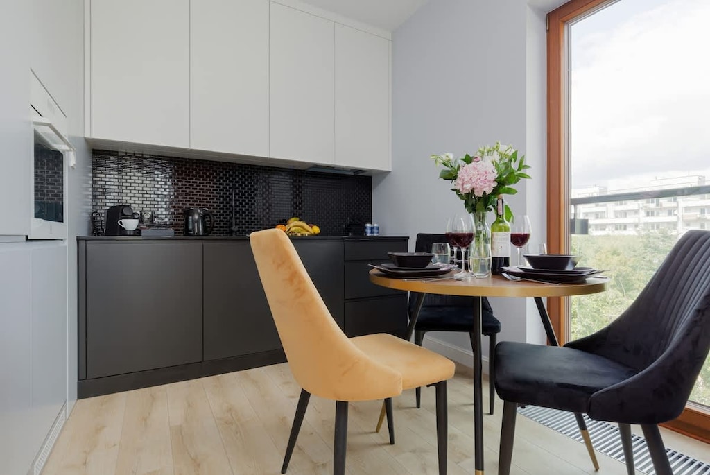 Kitchenette with a fridge with freezer, oven, dishwasher, induction hob, extractor hood, coffee machine, electric kettle, washing machine and dining area.