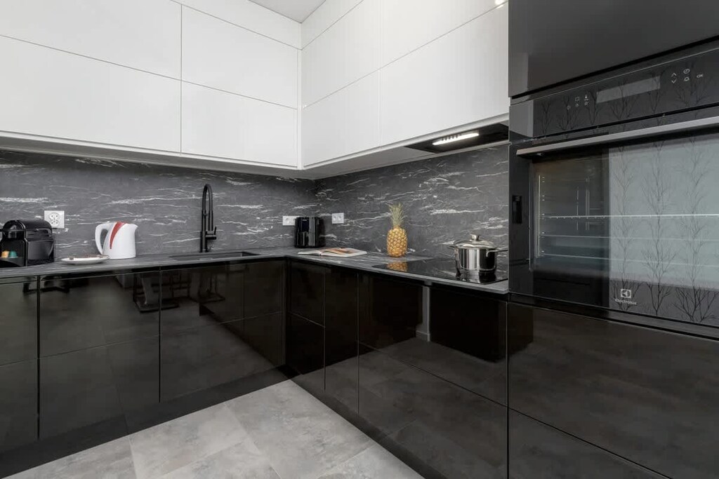 A contemporary kitchen with glossy black cabinetry, built-in appliances, and minimalist details.