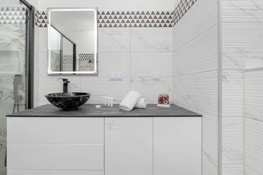 A sleek bathroom showcasing a floating vanity, a black countertop basin, and tasteful white tiling.
