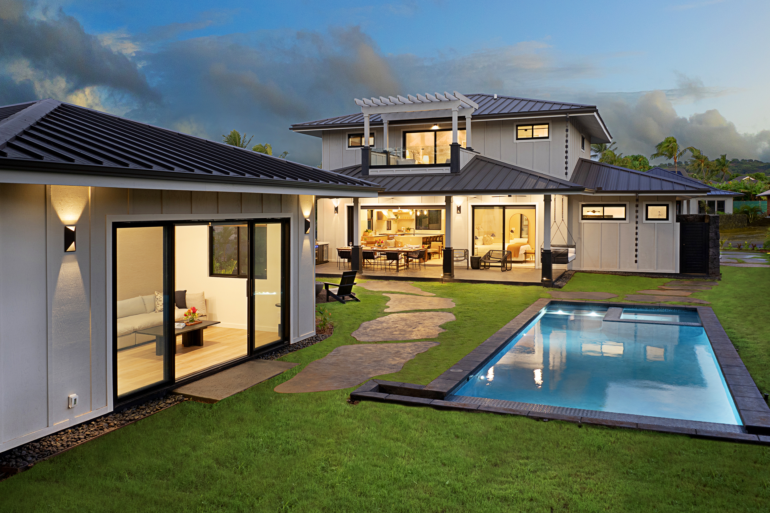 Dusk view of the property showcasing the pool, lush landscaping, and modern architecture.