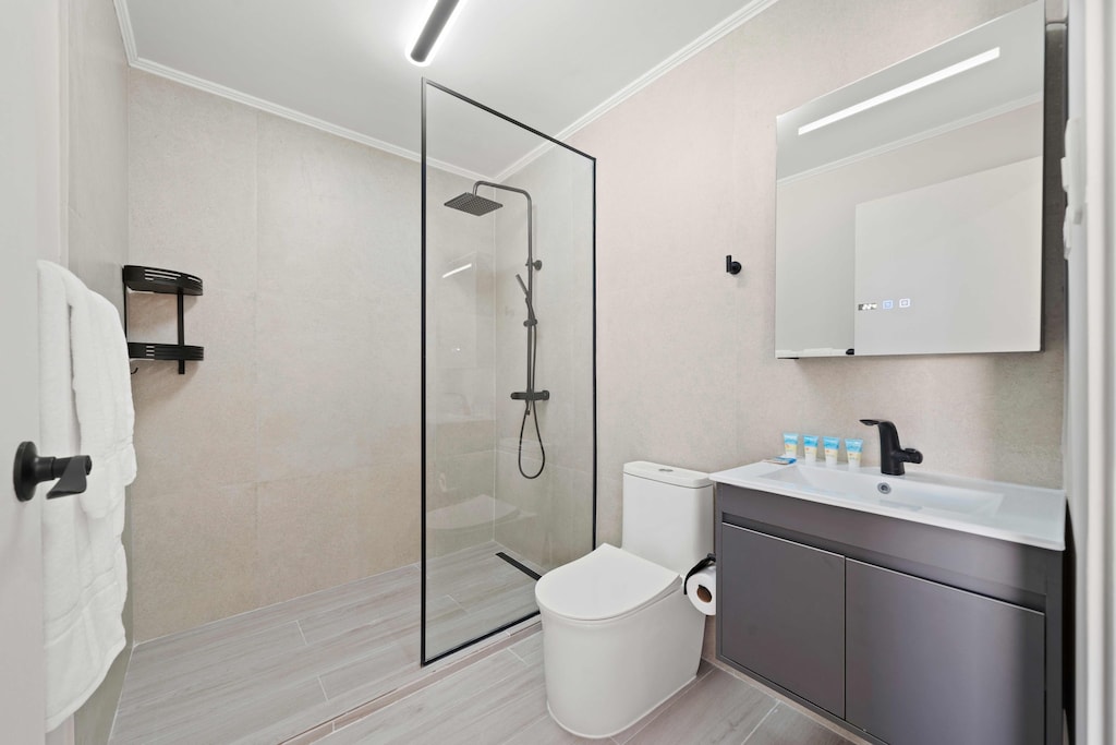- Sleek and modern, this bathroom boasts a minimalist walk-in shower with polished finishes - Matte black fixtures and clean lines exude elegance and style - A comfortable space crafted for refreshing starts and unwinding evenings