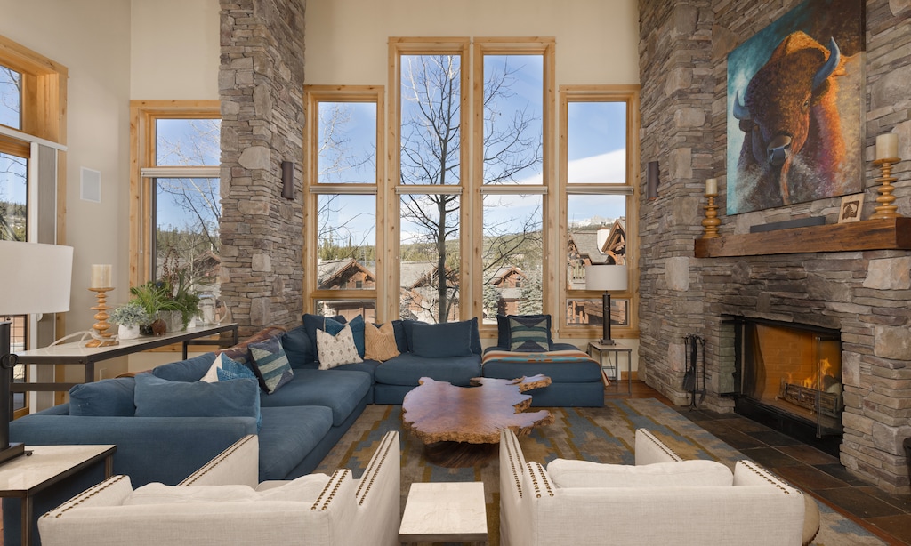 Unwind in this stunning living room with a crackling stone fireplace and panoramic mountain views through floor-to-ceiling windows.