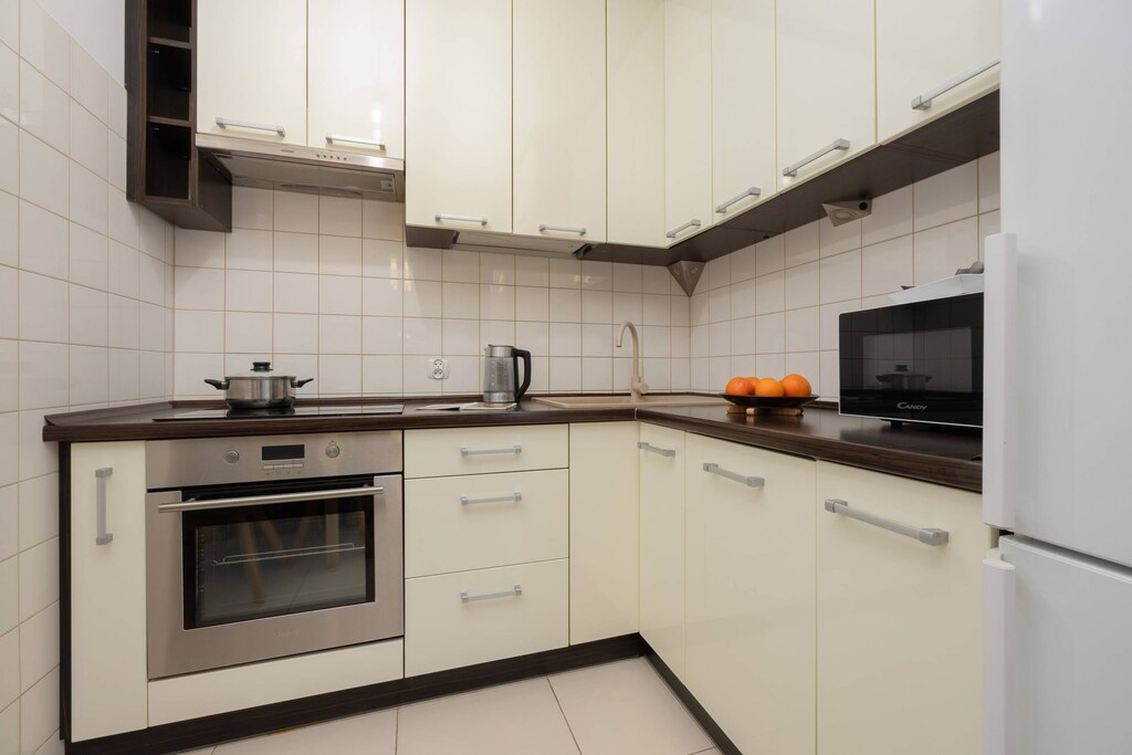 A modern kitchen with white cabinets, a built-in oven, and a sleek stovetop. The kitchen has a bright, functional design with tiled backsplash and countertops.