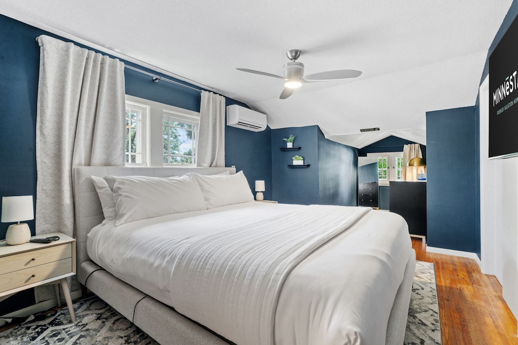 Unwind in your stylish bedroom with bold blue walls, crisp white linens, and modern comforts including ceiling fan and air conditioning.