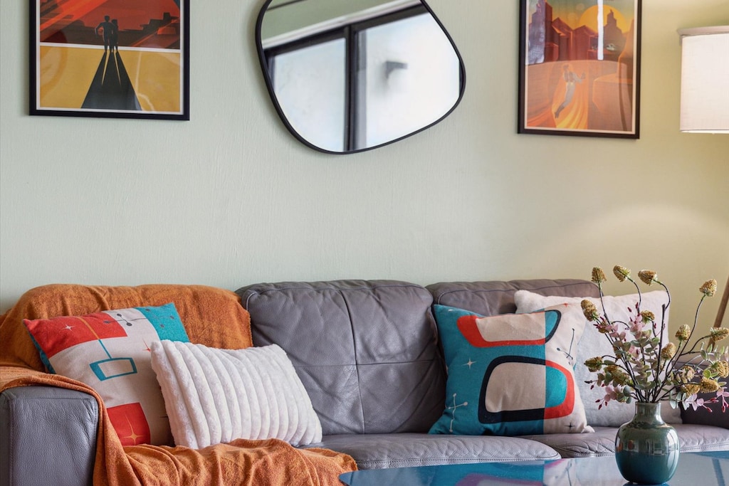 Relax on the stylish sofa, surrounded by vibrant décor and warm, inviting tones.