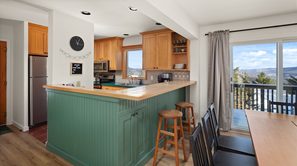 - Kitchen with wood cabinetry and stainless steel appliances   - Window above sink with scenic mountain and forest views   - Fully equipped space for convenient home-style cooking