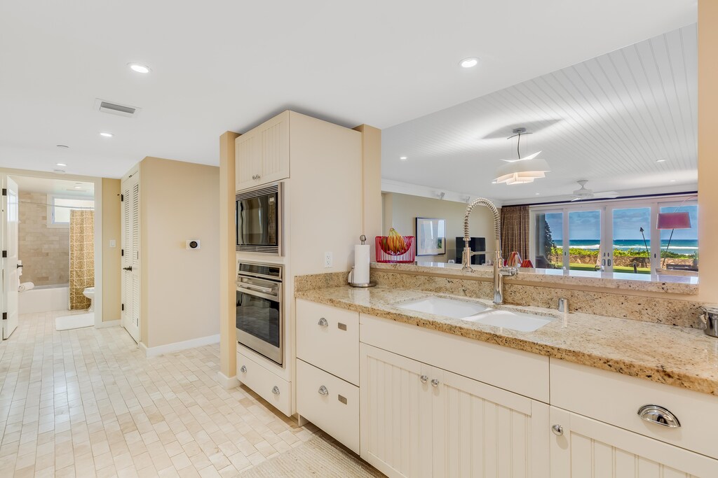 Kitchen overlooks the dining and living areas for seamless gatherings and island living.