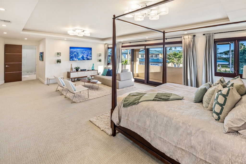 Elegant primary suite with a four-poster bed and the lounge area that provides a comfortable space to relax and recharge.