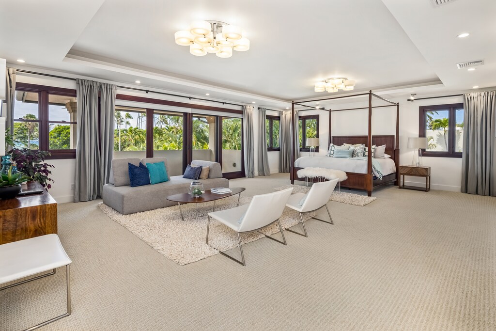 The primary suite offers a cozy sitting area with wall-to-wall windows and lush garden views.