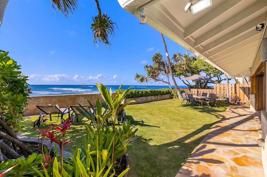 Oceanside lawn with umbrella-shaded seating and panoramic views—ideal for morning coffee or sunset cocktails.