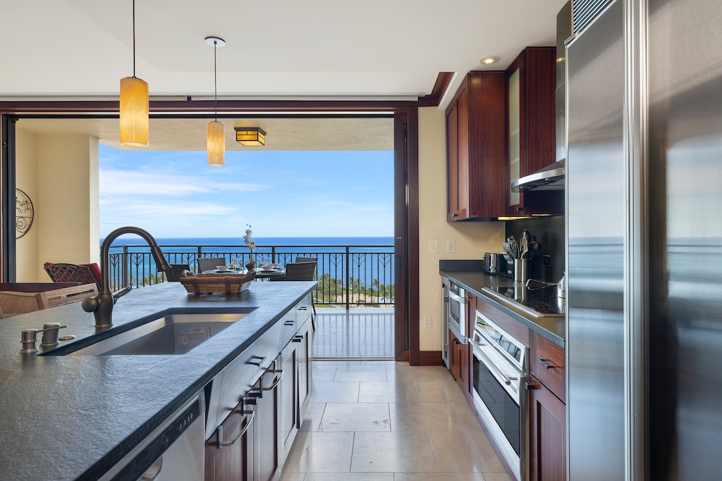 The kitchen is equipped with high-end stainless steel appliances, including a built-in oven, microwave, and a spacious refrigerator, all perfectly situated to enjoy the ocean view.