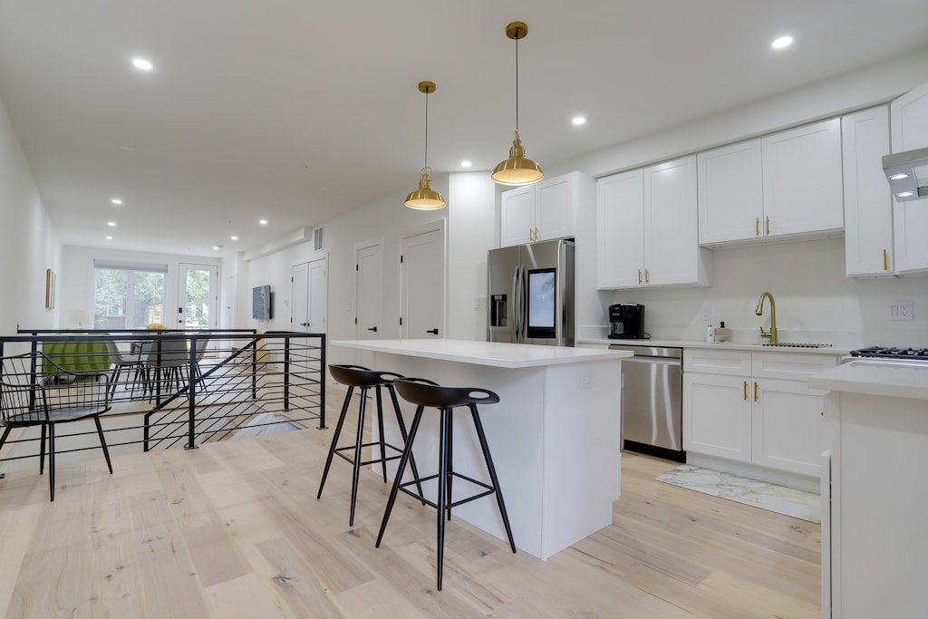 Kitchen with a view of the living room. Kitchen has an island with modern appliances. 