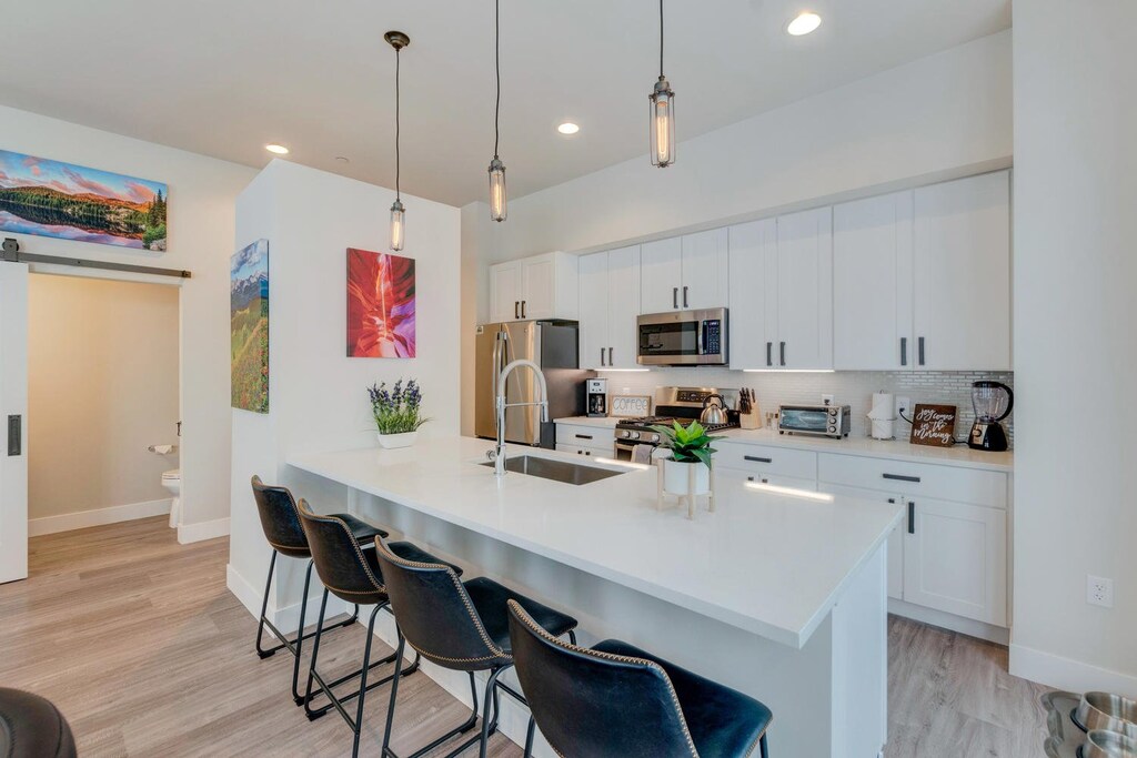 Kitchen Counter with Stools, Refrigerator, and Microwave.