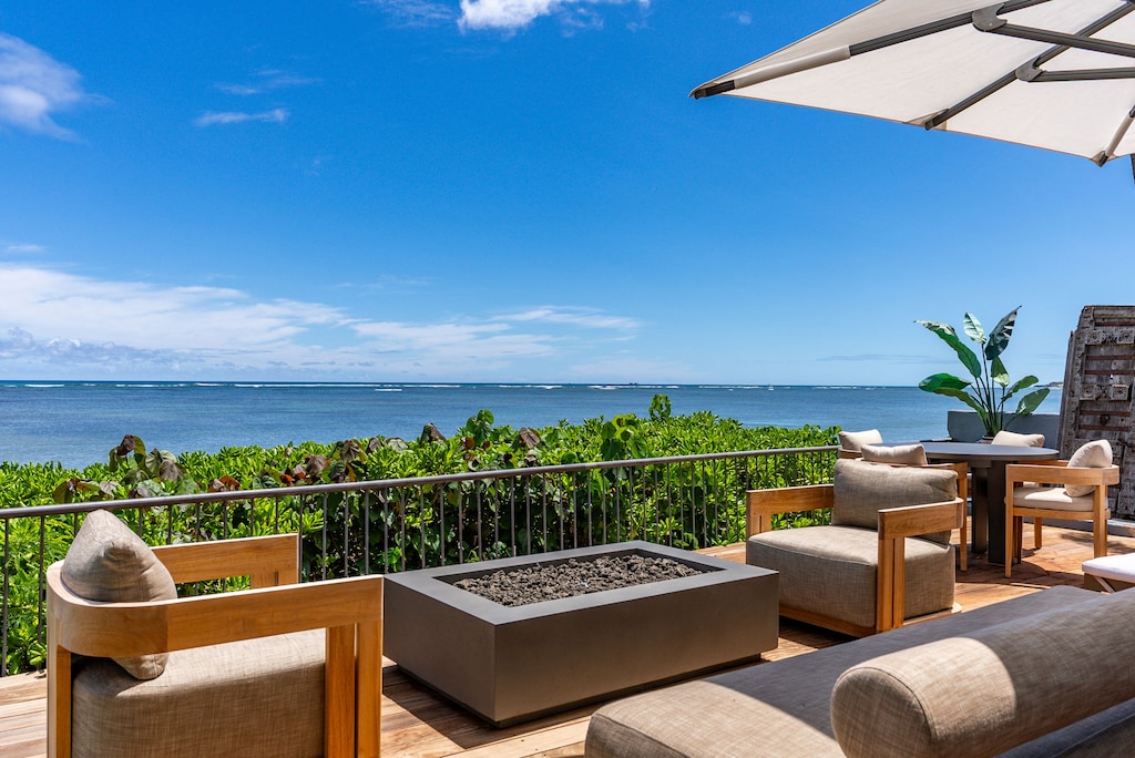 Oceanfront deck at Wailupe Beachfront Getaway with fire pit lounge and panoramic reef views.