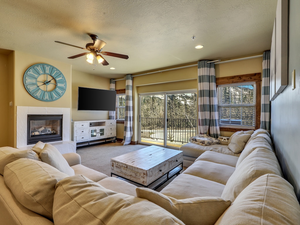 View of Living Room with Ceiling Fan, Smart TV with Roku, Gas Fire Place, Sectional Sofa, Coffee Table, Access to Private Balcony