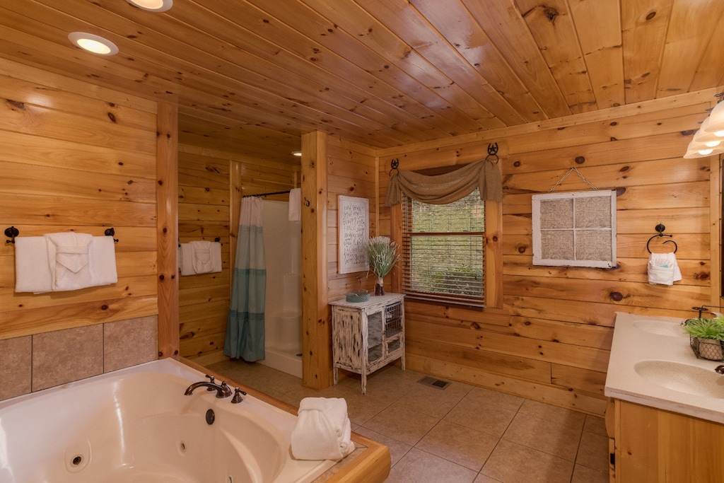 Bathroom with jacuzzi, walk in shower, and his and hers sink