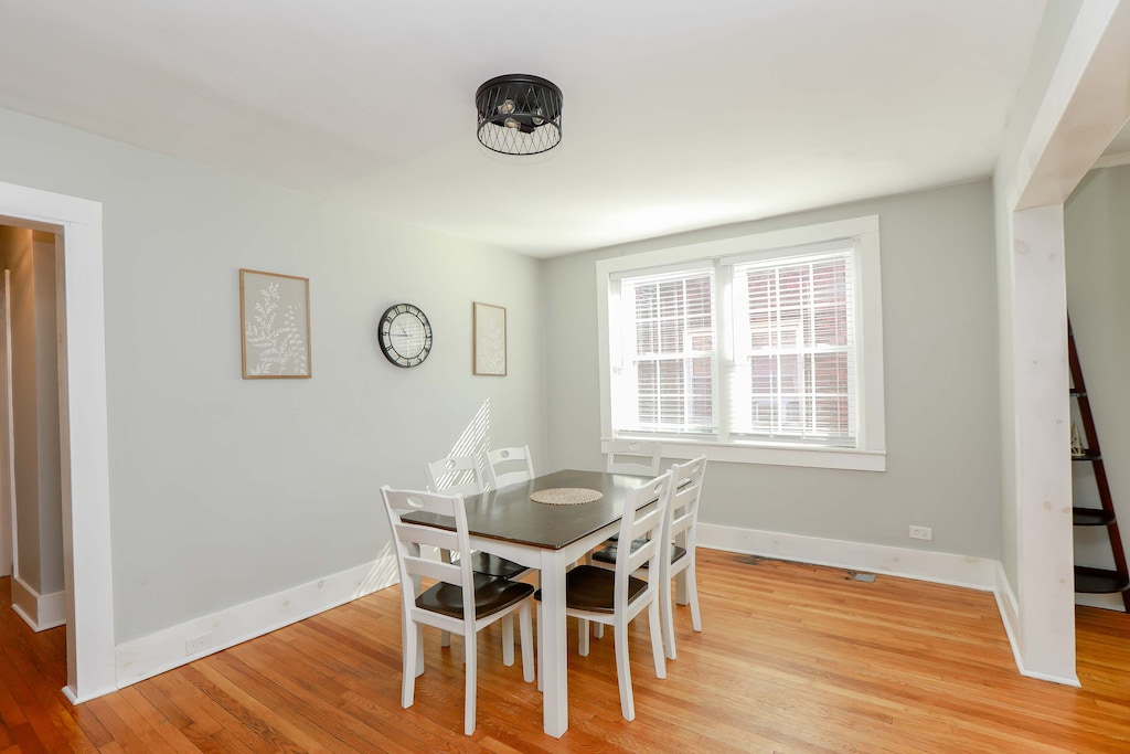 Dining room table with seating for six, windows and artwork. 
