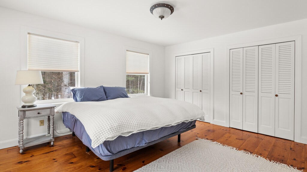 - Bedroom with plush bed and fresh blue bedding   - Large windows bring in peaceful natural views   - Comfortable retreat with warm wooden floors