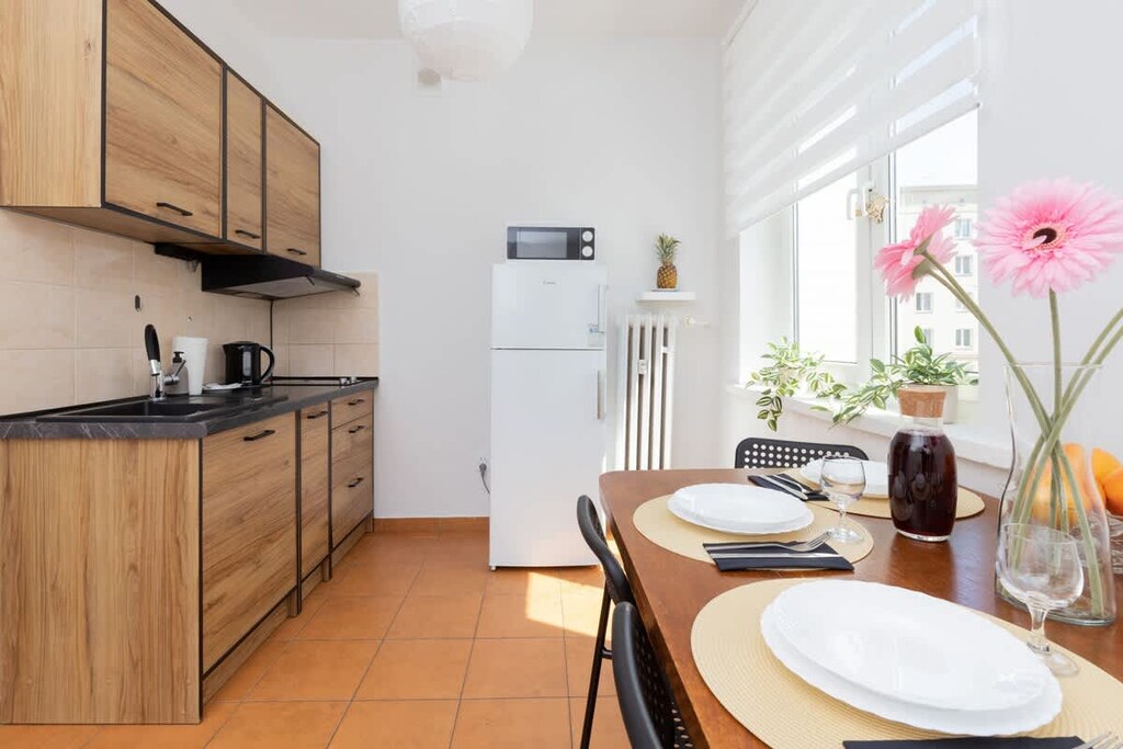 A small dining table set for two, decorated with fresh flowers, oranges, and a juice bottle for a lively atmosphere.