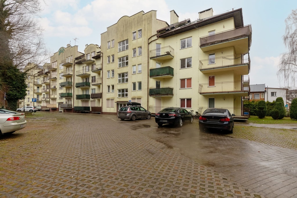 An exterior view of the building, showcasing the parking area and surroundings.


