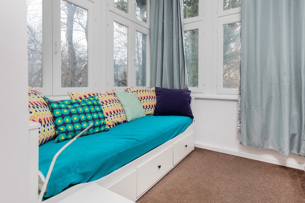 A bright window seat with turquoise cushions, offering a comfortable reading nook.
