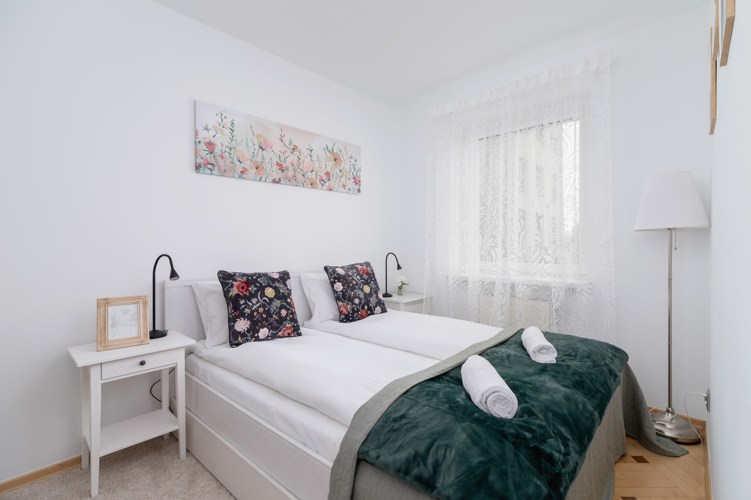 A cozy bedroom with a comfortable bed, green blanket, and soft decor.
A cozy bedroom with a comfortable bed, green blanket, and soft decor.
