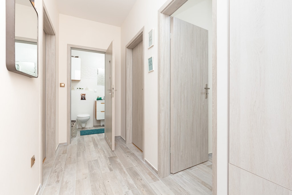 A spacious hallway with bright flooring and minimalist decor leading to various rooms.
