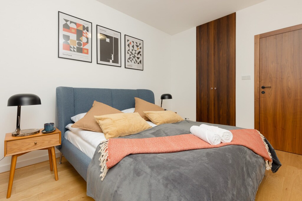 Modern bedroom with a comfortable double bed, colorful bedding, and minimalist decor, perfect for relaxation.
