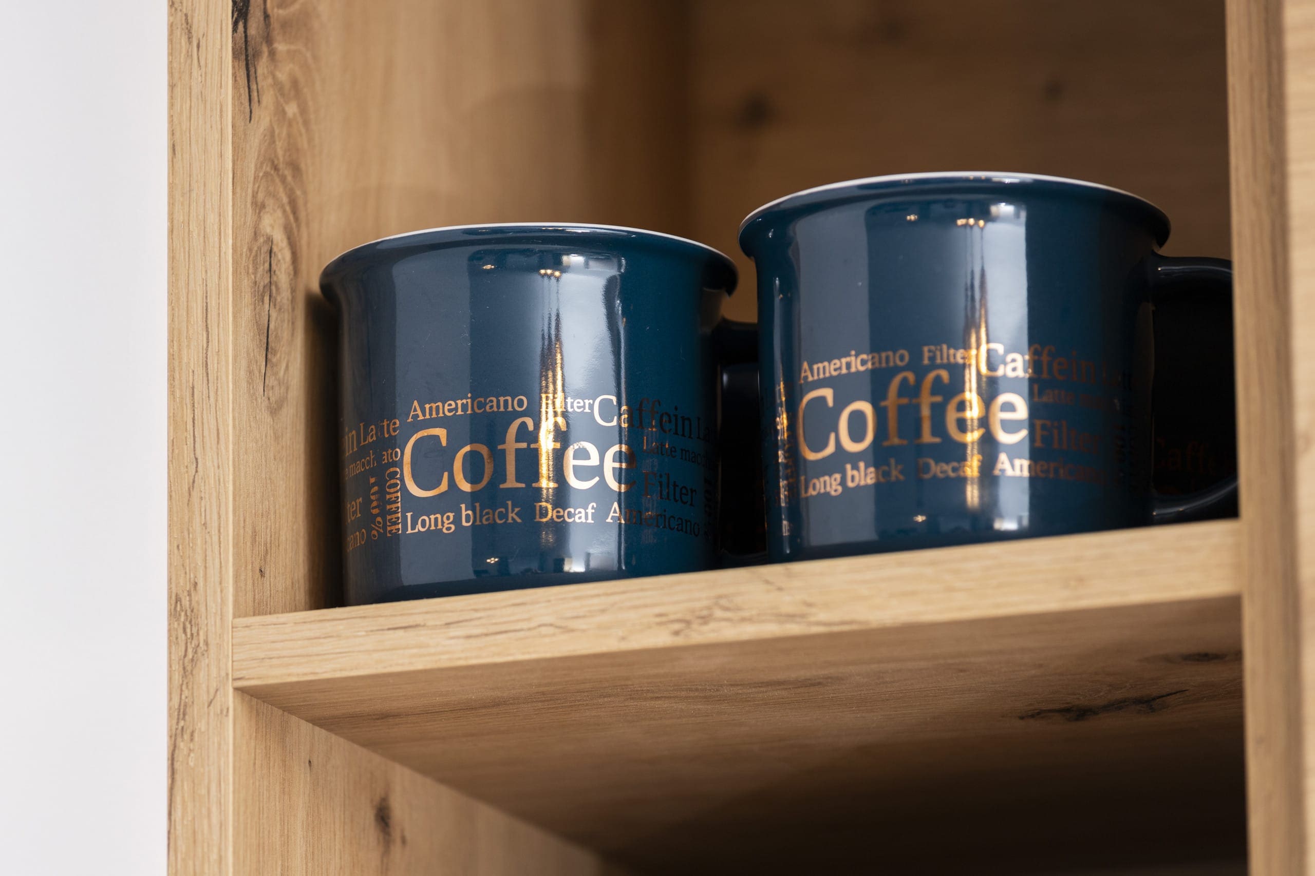 A close-up of two coffee canisters placed on a wooden shelf.
